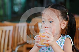 Closeup of little girl drinking Orange juice with looking out