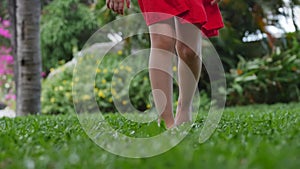 Closeup little girl playing outdoors go on bright green beautiful grass with yellow flowers, outdoors at high angle feet