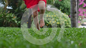 Closeup little girl playing outdoors runs on bright green beautiful grass with yellow flowers, outdoors at high angle