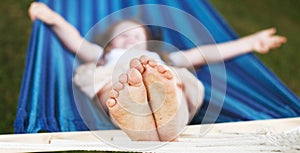 closeup of little girl's feet relaxing in the blue hammock during her summer vacation in back yard