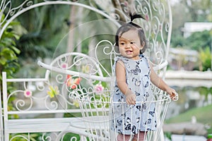 Closeup little girl stand on steel bicycle basket for decorate in the garden background with smile face