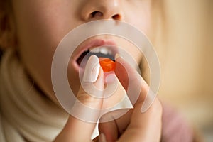 Closeup of little girl taking medicine in pill