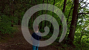 Closeup of little girl walking on a footpath, alone in dark, spooky forest