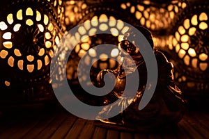 Closeup of a little golden monk statue illuminated by warm candlelight