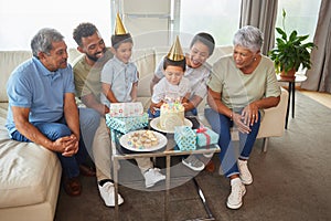 Closeup of a little mixed race boy blowing the candles on a cake at a birthday party with his little brother, parents