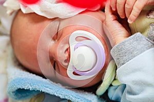 Closeup of little newborn sleeping with teat in mouth