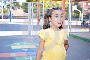 Closeup of a  little pretty girl sticking tongue out with hopscotch in the background