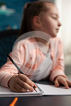 Closeup of little schoolgirl studying online lesson working at mathematics homework