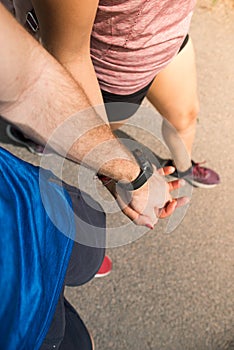 Closeup of loving couple holding hands while walking together. They wear sportswear and smart watch. Excursion and hiking concept