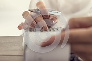 Closeup low angle view of a woman using a manual adding machine