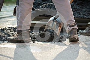 Closeup low angle view of worker arranging fresh asphalt mixture