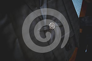 Closeup of a luxurious wristwatch and a bow tie on a gray suit jacket