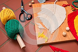 Closeup of macrame leaf in the process of shaping and different craft supplies.