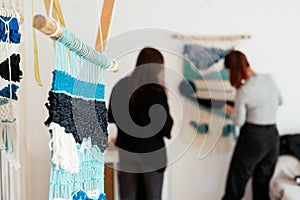 Closeup of macrame wall-hanging decorations weaved by two females