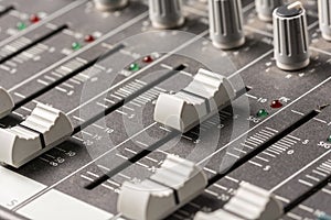 Closeup macro audio mixing console knobs and sliders.