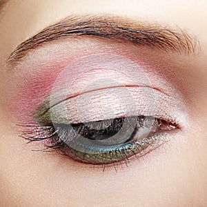 Closeup macro image of human woman eye with pink and green makeup