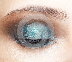 Closeup macro shot of closed human female eye. Girl with perfect skin and  blue eyes shadows