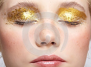 Closeup macro shot of closed human female face with yellow smoky eyes beauty makeup