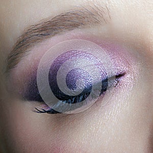 Closeup macro shot of human female eye. Woman with lilac beauty eyes makeup