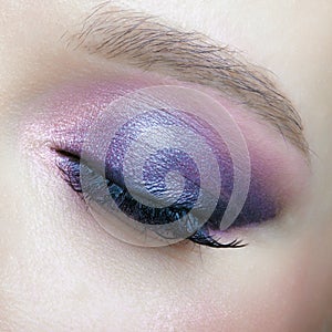 Closeup macro shot of human female eye. Woman with lilac beauty eyes makeup