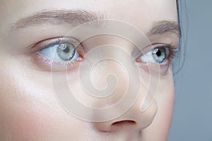 Closeup macro shot of human female face. Woman with blue eyes and natural face beauty makeup