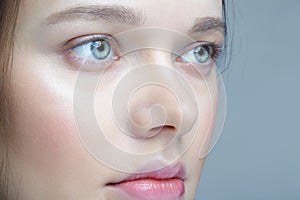 Closeup macro shot of human female face. Woman with blue eyes and natural face beauty makeup