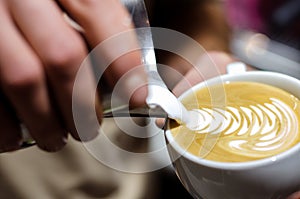 Closeup of making latte art with milk in espresso cup