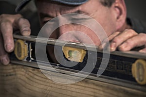 Closeup of male carpenter using level tool on wood board