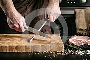 Closeup of male chef hands sharpen a big chef`s knife