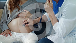 Closeup male doctor checking heartbeat of unborn child in pregnant woman belly