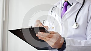 Closeup of male doctor hand writing a medical prescription