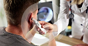 Closeup of male ear being examined with an otoscope doctor