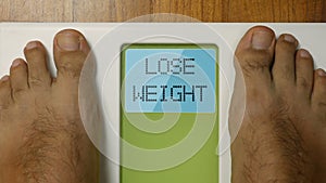 Closeup male feet on scale LOSE WEIGHT display at morning 4k footage top view