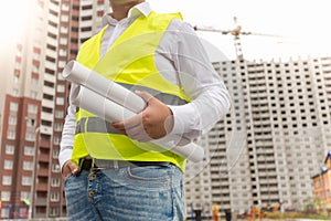 Closeup of male foreman holding rolled blueprints