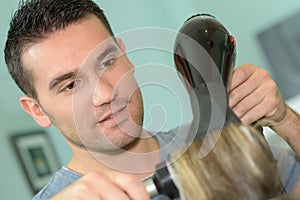 closeup male hairstylist using blowdryer