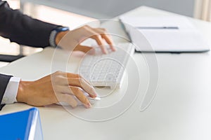 Closeup of male hand clicking wireless digital mouse working with desktop computer at office desk