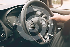 Closeup male hand driving a car with interior luxury dashboard and steering wheel