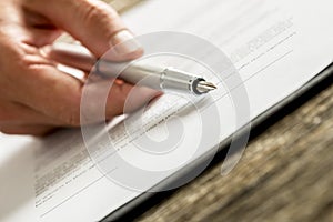 Closeup of male hand holding an ink pen pointing with its end on