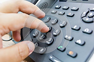 Closeup of male hand holding telephone receiver while dialing a telephone number to make a call