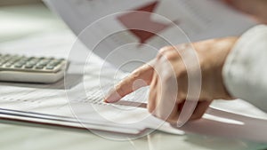 Closeup of male hand pointing to figures written on a document