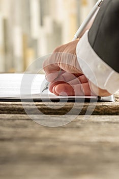 Closeup of male hand signing contract or application form on a r