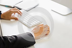 Closeup of male hand working with desktop computer and clicking wireless digital mouse at office desk