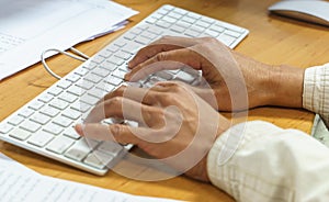 Closeup of a male hands busy typing on a keyboard computer.
