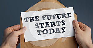 Closeup of a male hands holding craft envelope with text The future starts today on blue background