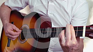Closeup male hands, middle-aged man plays acoustic guitar music, teacher teaches how to play musical instrument, blogger