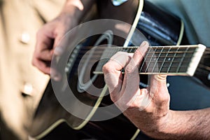 Closeup of male hands playing acoustic guitar sitting near tent outdoors. Selective focus. Romance and songs with guitar