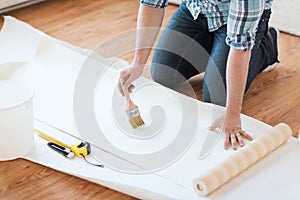 Closeup of male hands smearing wallpaper with glue