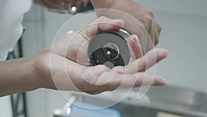 Closeup of male hands spin the mill with pepper in the restaurant kitchen