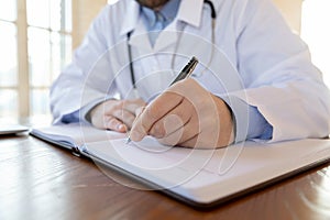 Closeup of male physician filling paper medical journal by hand