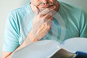 Closeup of male reading book and stroking chin photo